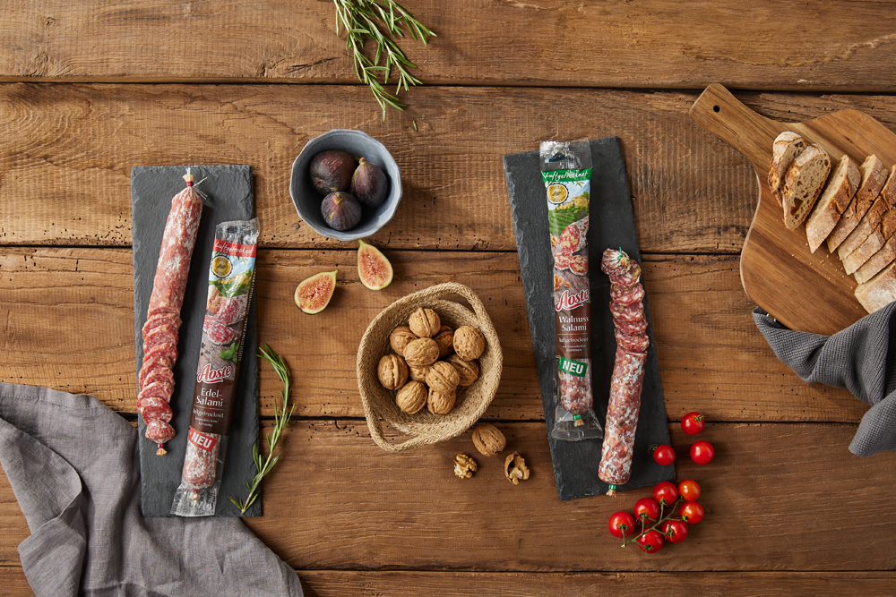 Aoste Salami mit Walnüssen Tomaten und Brot auf rustikalem Holztisch