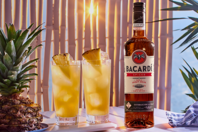 BCARDÍ Spiced Rum mit zwei Gläsern mit Cocktail und Ananas daneben